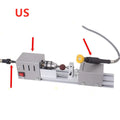 Silver metal mini manual woodworking lathe with carving knives on a workbench.