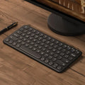 Ultra-thin white wireless keyboard and mouse set with USB receiver on a wooden desk.