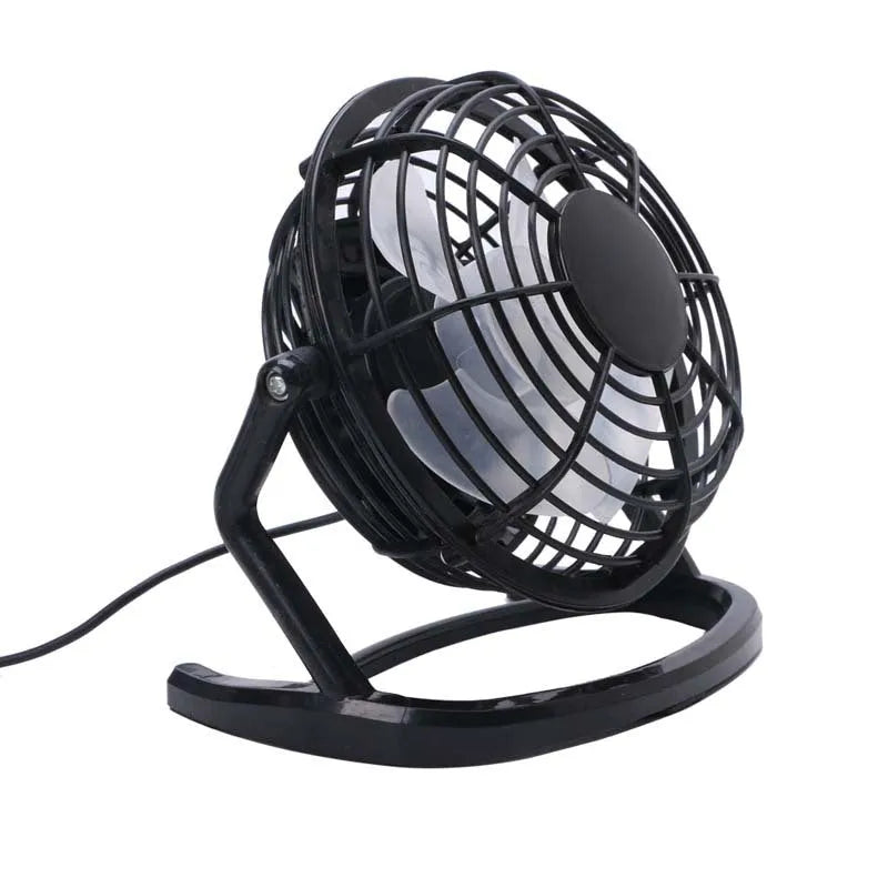 Compact black mini USB desk fan with adjustable tilt, placed next to a laptop.