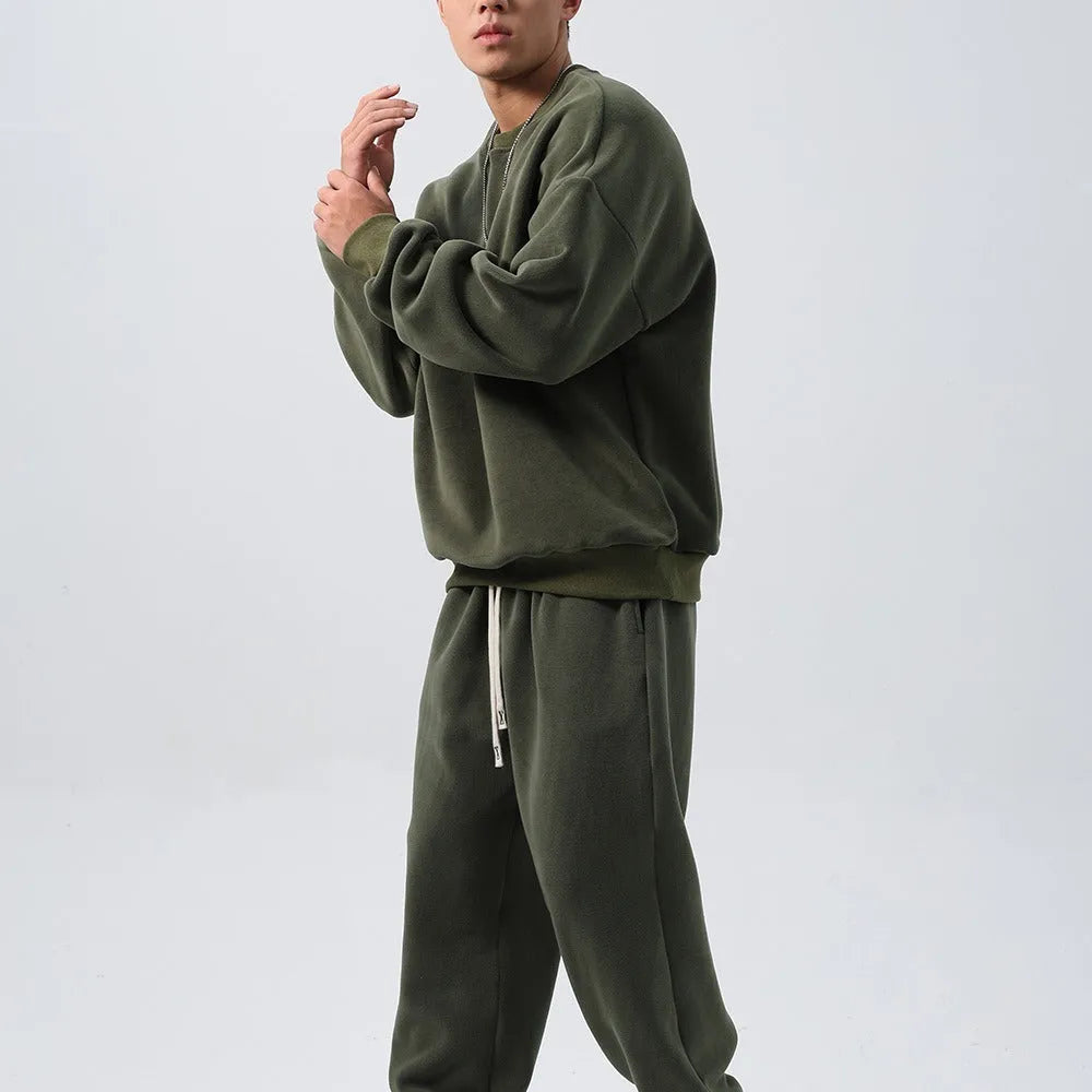Men's black polar fleece sports suit with loose crew neck jacket and padded trousers on a hanger.