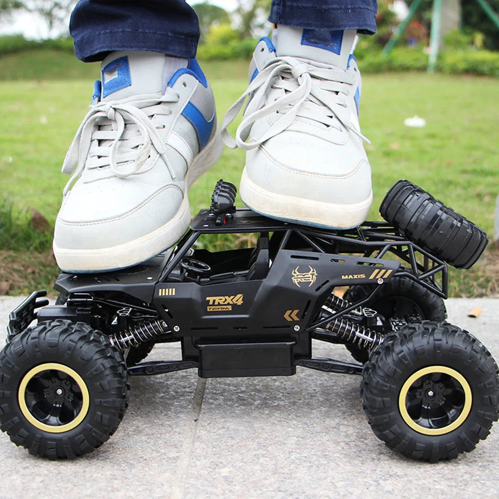 Large black or silver 4WD remote control climbing car on off-road terrain with wireless remote.