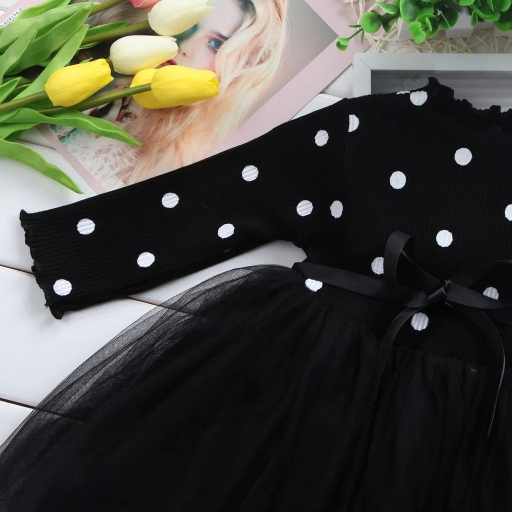 Baby girl wearing a long sleeve black lace tutu dress for a christening or birthday party.
