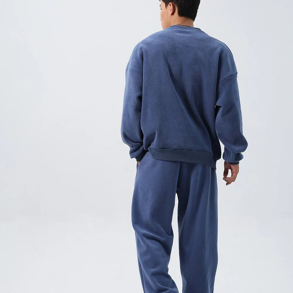 Men's black polar fleece sports suit with loose crew neck jacket and padded trousers on a hanger.