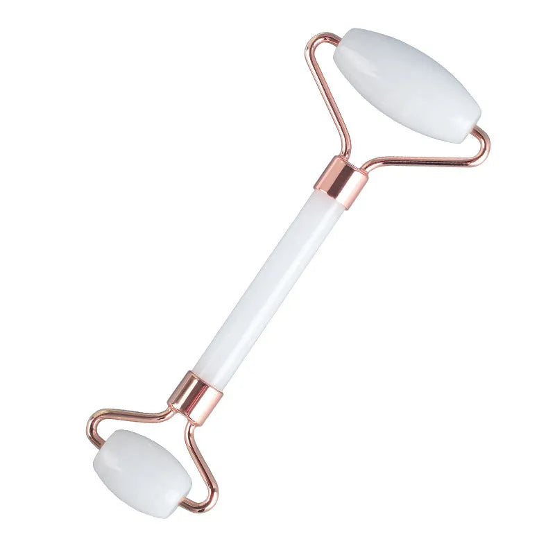 White jade double-headed facial roller and scraping board set on a plain surface.