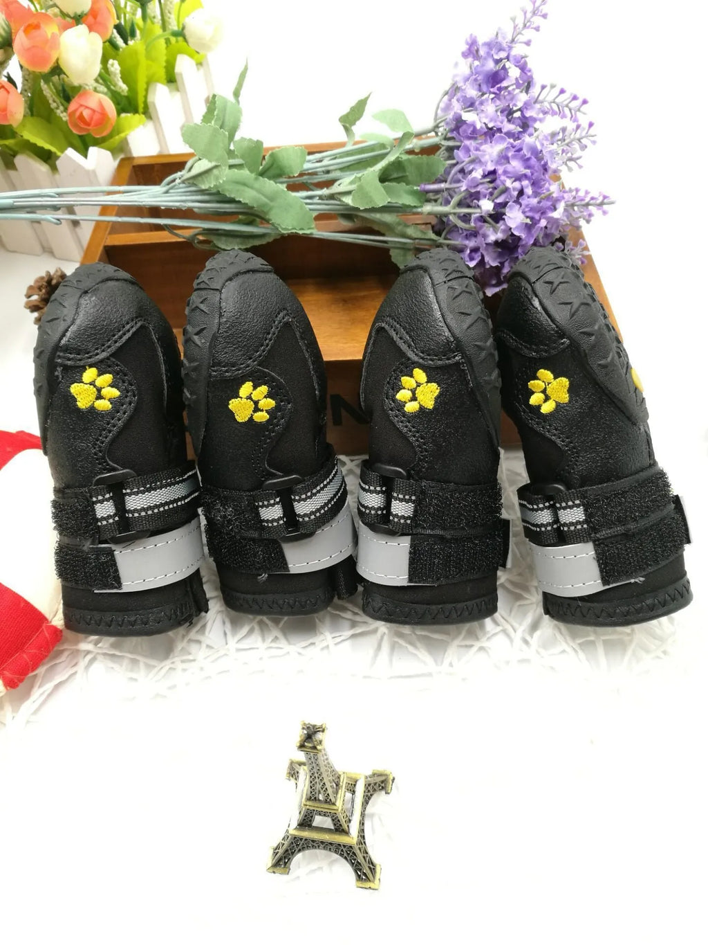 Black dog shoes with waterproof PVC sole and adjustable fuzzy belt on a dog's paw