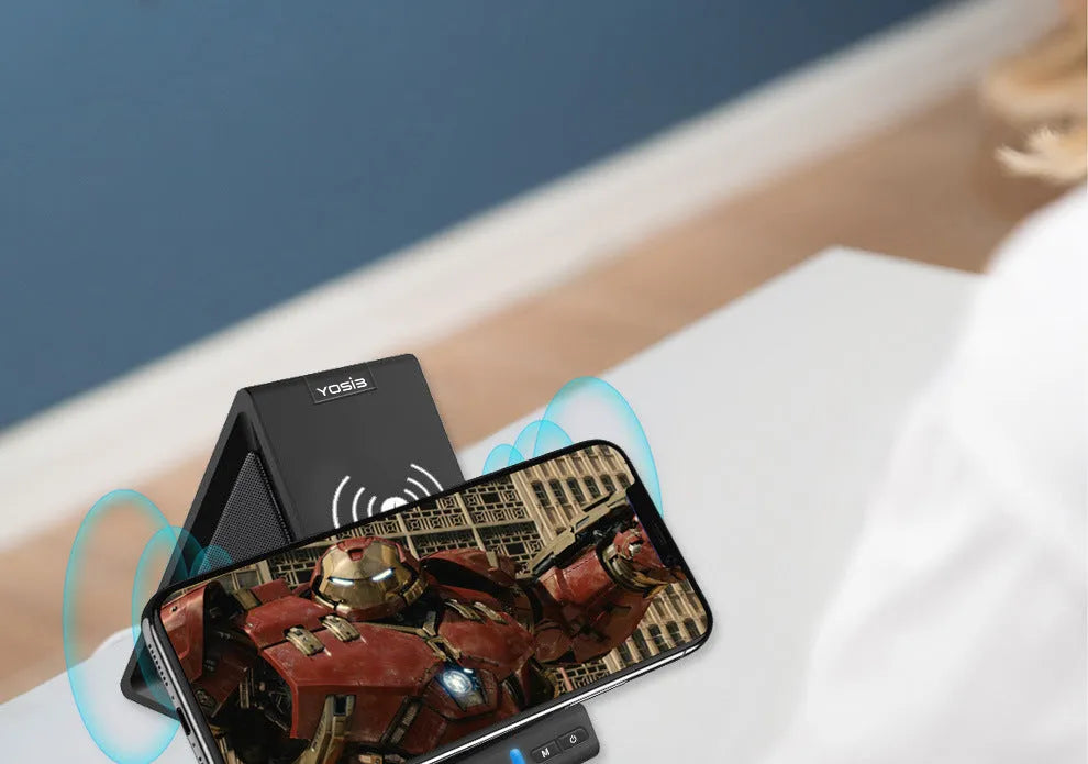 Black multifunctional Bluetooth speaker with integrated phone holder and wireless charging pad showing front and side views.