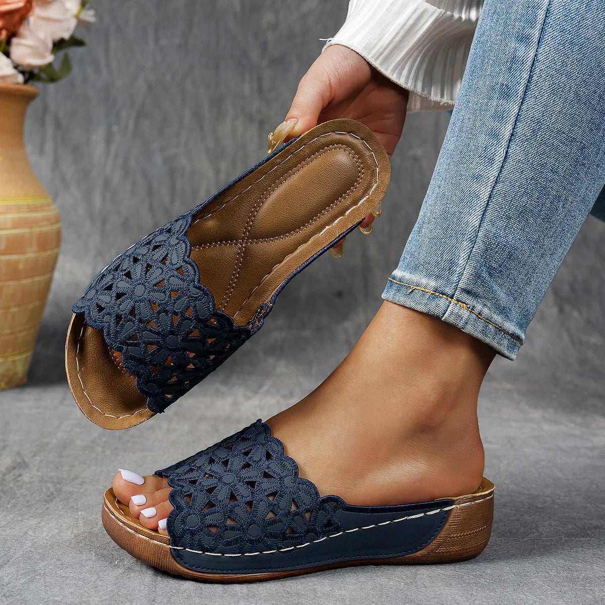 Women's black wedge beach slipper with floral cutouts and fish mouth toe shape on a rubber sole.
