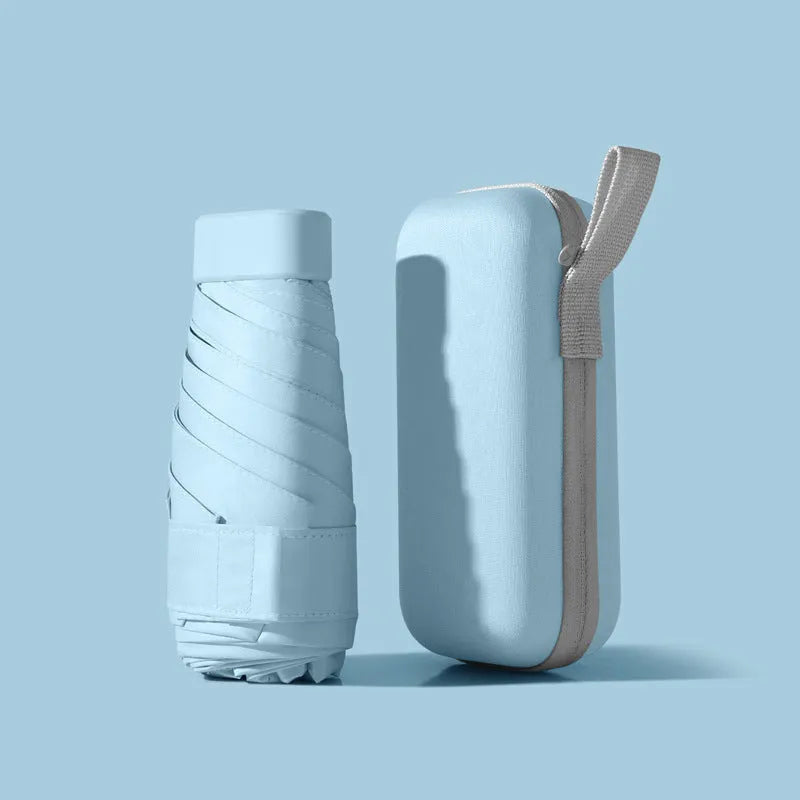 Ultra-light six-fold sun umbrella open, showing NC fabric canopy and rubber handle, next to its compact folded size in a capsule box.