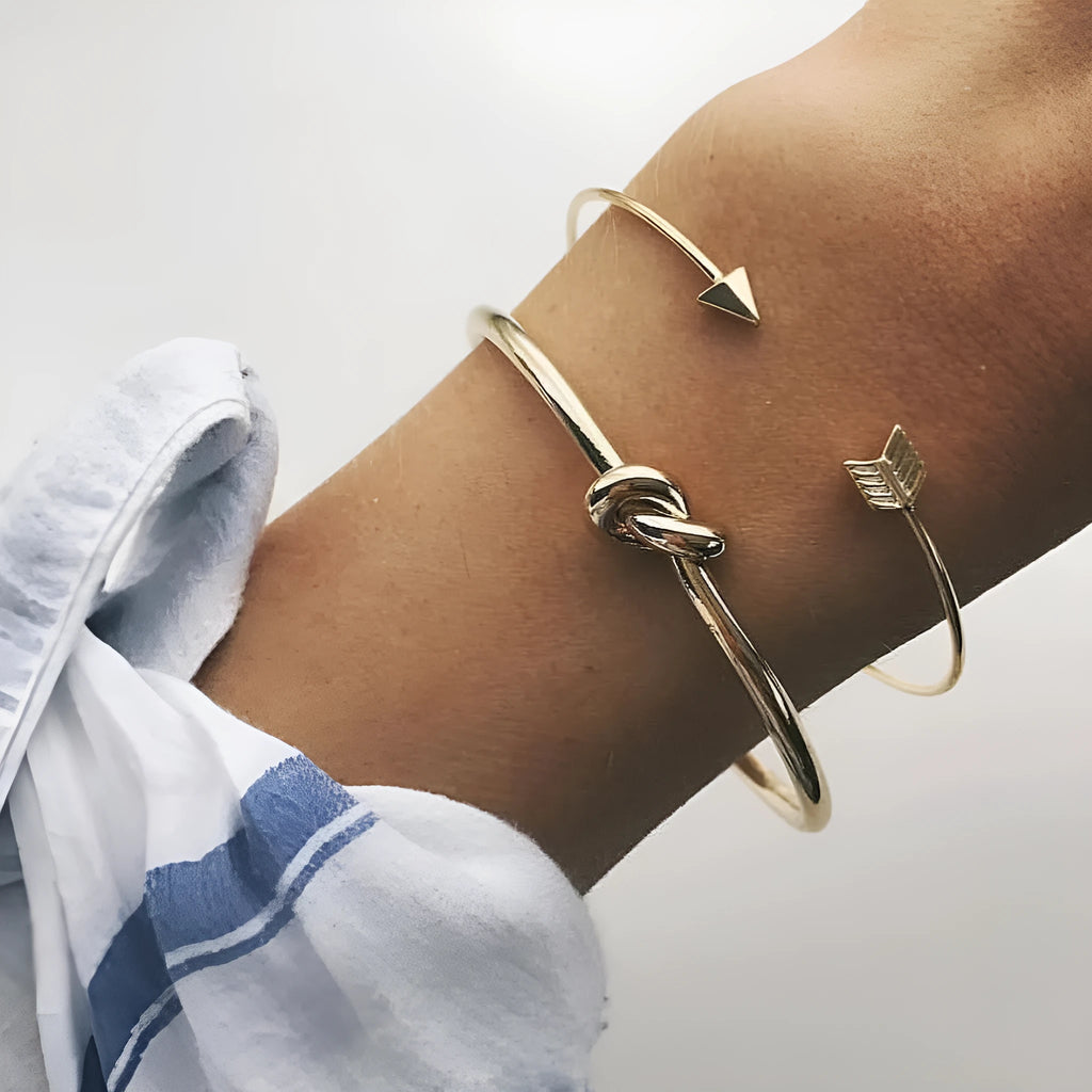 Gold-coloured women's vintage cuff bracelet with an arrow knot detail on an alloy band.