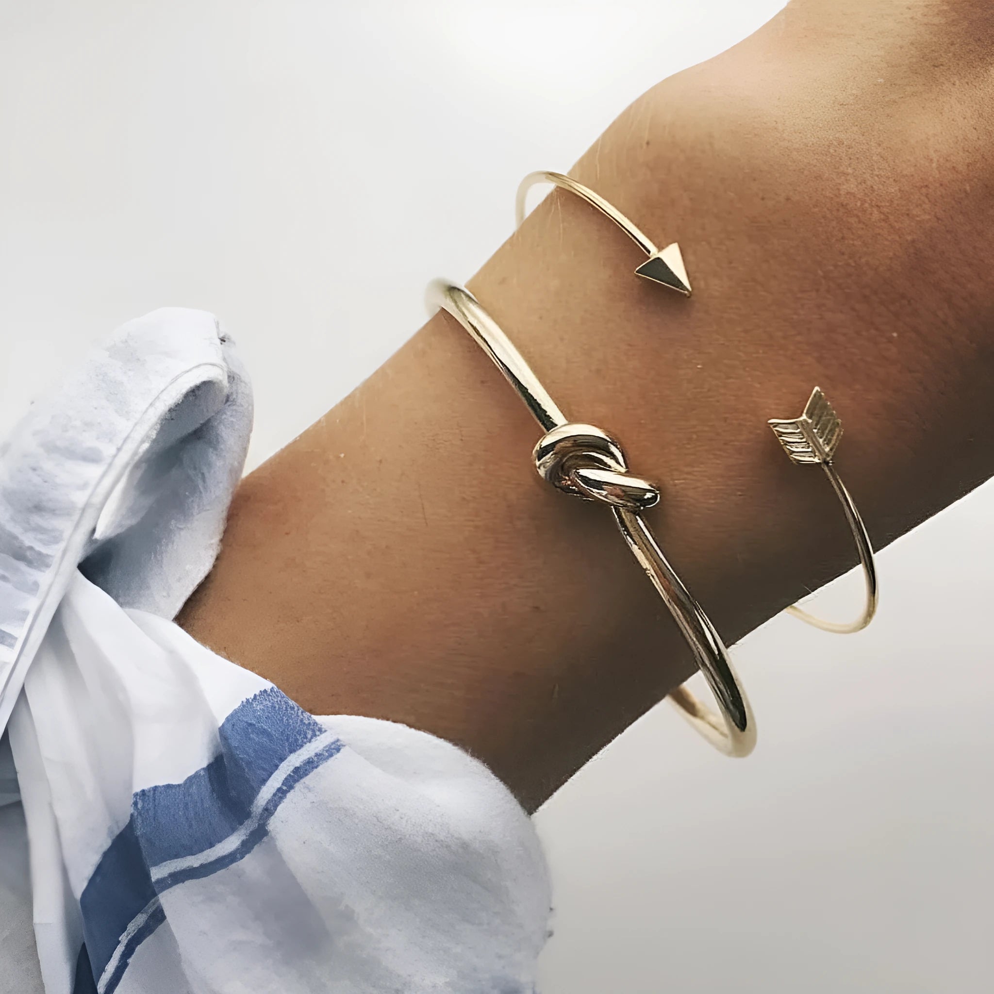 Gold-coloured women's vintage cuff bracelet with an arrow knot detail on an alloy band.