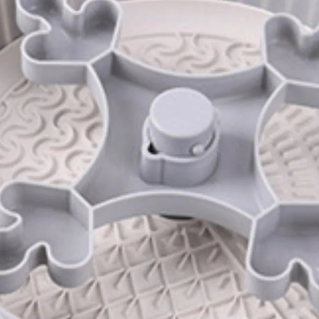 Grey rotating pet slow feeder bowl with a blue silicone windmill-pattern licking mat attached.
