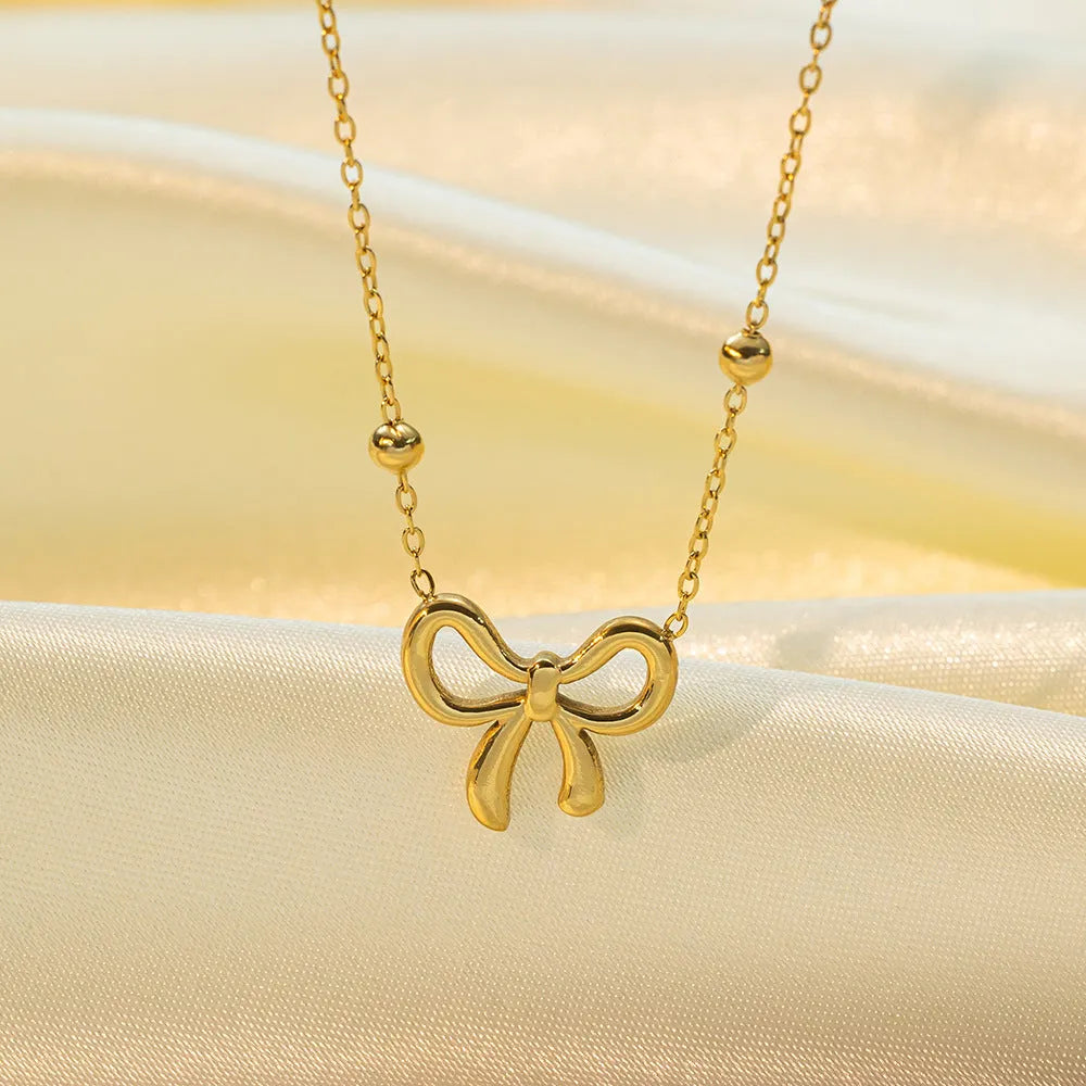 Gold bow necklace with cross chain design showing adjustable length from 41 to 50cm