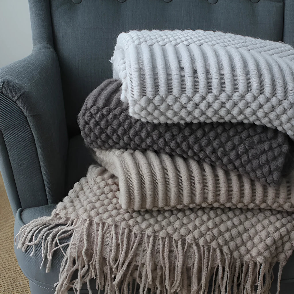 Small grey polyester nap blanket folded on a sofa, showing its texture and size.
