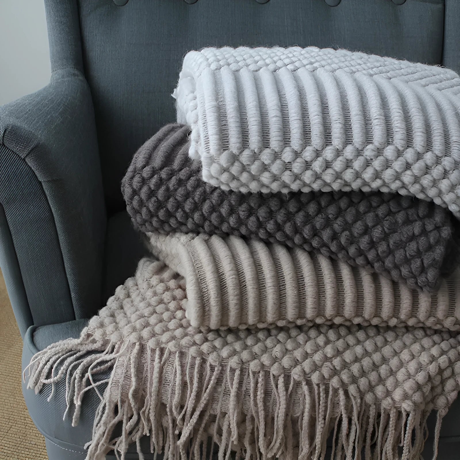 Small grey polyester nap blanket folded on a sofa, showing its texture and size.
