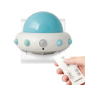 Remote control UFO shaped bedside night light in blue, pink, or white on a bedside table.