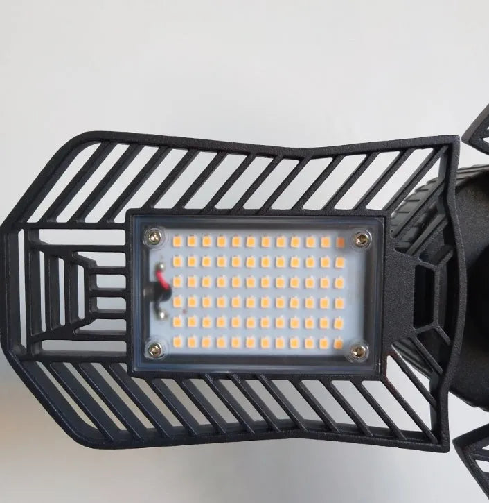 A foldable industrial LED garage flood light with a die-cast aluminum body, shown in a workshop setting.