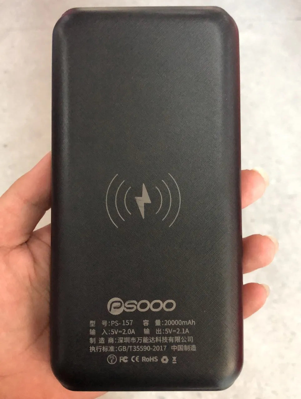Black portable power bank with wireless charging pad on top, three USB ports, and an LED flashlight.