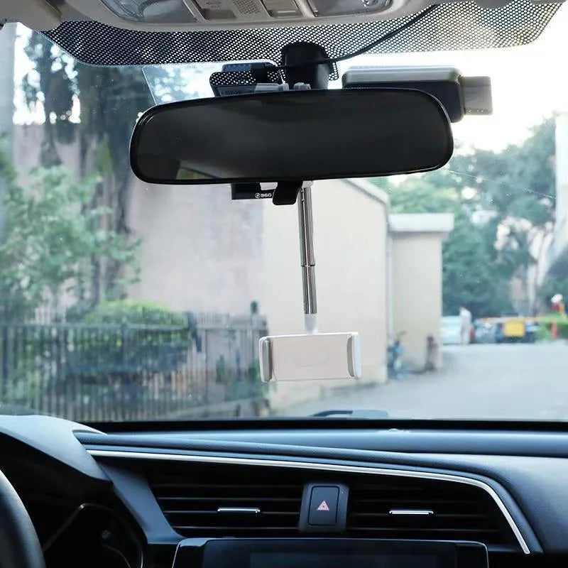 Black ABS plastic mobile phone bracket mounted on a car rearview mirror, holding a smartphone.