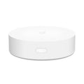 White circular Xiaomijia smart home gateway hub with UK plug on a table.