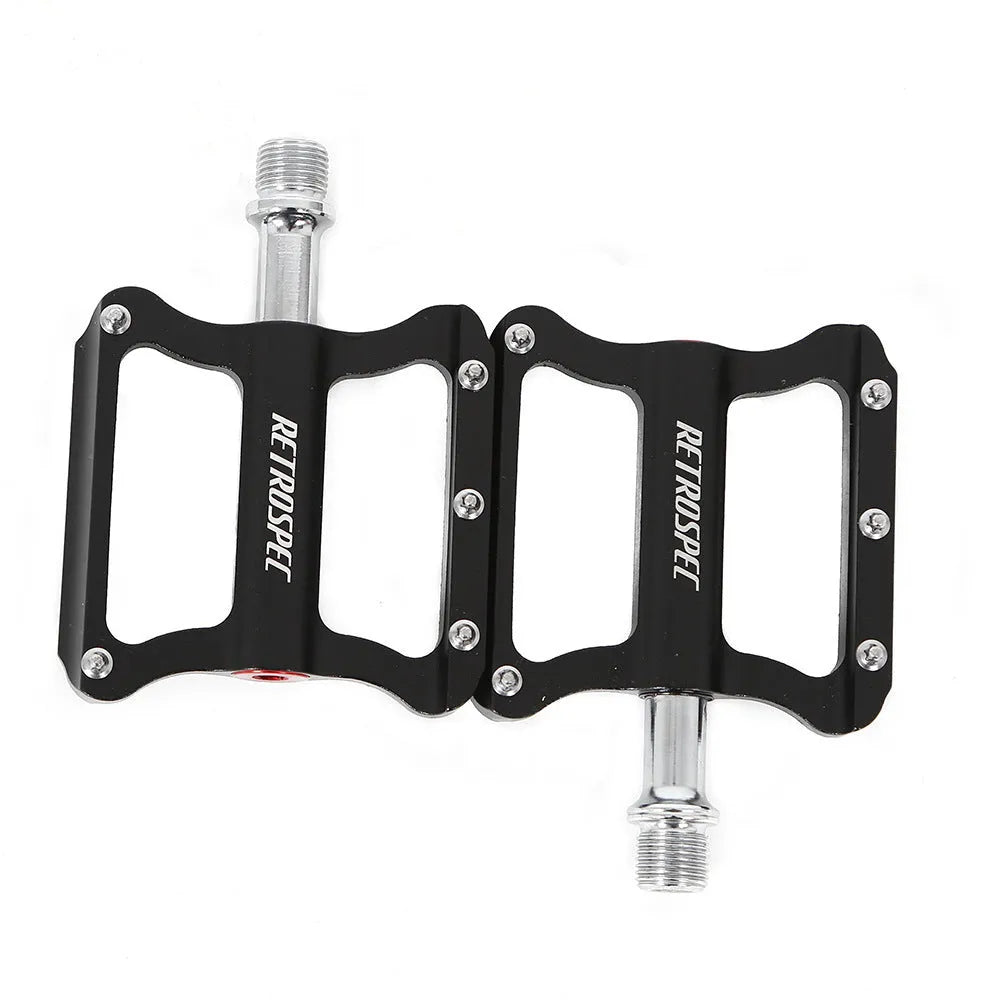 Pair of black CNC aluminium mountain bike pedals with sealed bearings and anti-skid nails on a white background