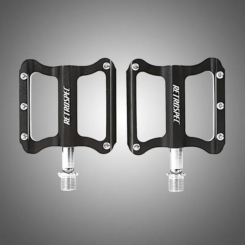 Pair of black CNC aluminium mountain bike pedals with sealed bearings and anti-skid nails on a white background