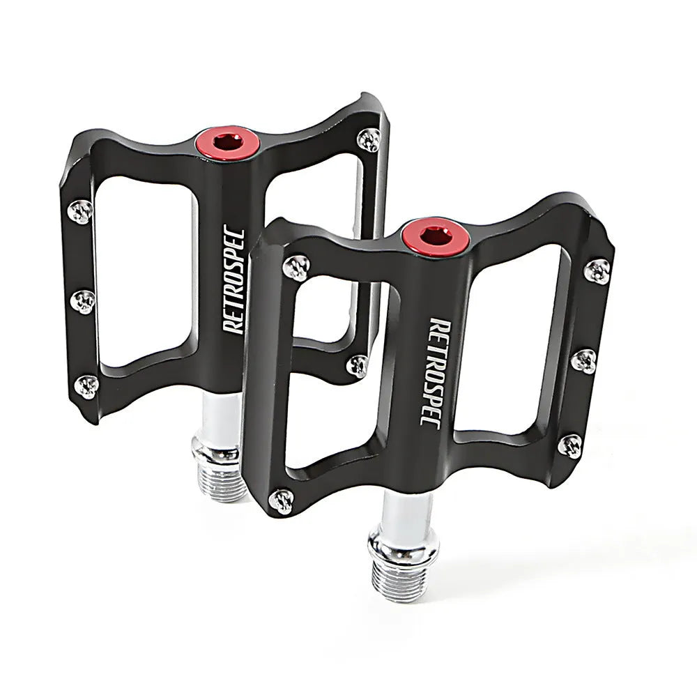 Pair of black CNC aluminium mountain bike pedals with sealed bearings and anti-skid nails on a white background