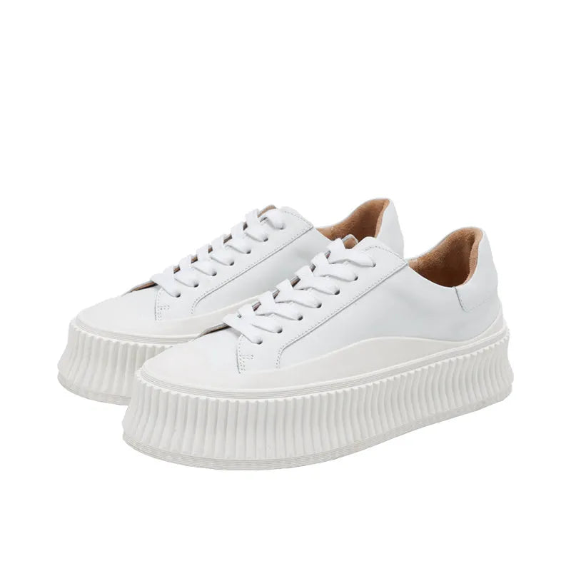 Women's black suede platform trainers with thick white soles and cross-lace design on a white background.