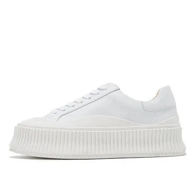 Women's black suede platform trainers with thick white soles and cross-lace design on a white background.