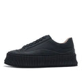 Women's black suede platform trainers with thick white soles and cross-lace design on a white background.