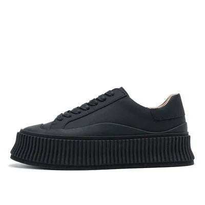 Women's black suede platform trainers with thick white soles and cross-lace design on a white background.