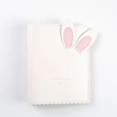 Small pink loose-leaf photo album with rabbit-themed pages, shown next to a 3-inch photograph for scale.
