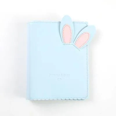 Small pink loose-leaf photo album with rabbit-themed pages, shown next to a 3-inch photograph for scale.