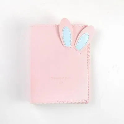 Small pink loose-leaf photo album with rabbit-themed pages, shown next to a 3-inch photograph for scale.