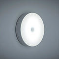Compact round motion sensor LED night light with USB charging cable and adhesive mounting tape