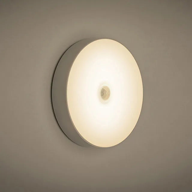 Compact round motion sensor LED night light with USB charging cable and adhesive mounting tape