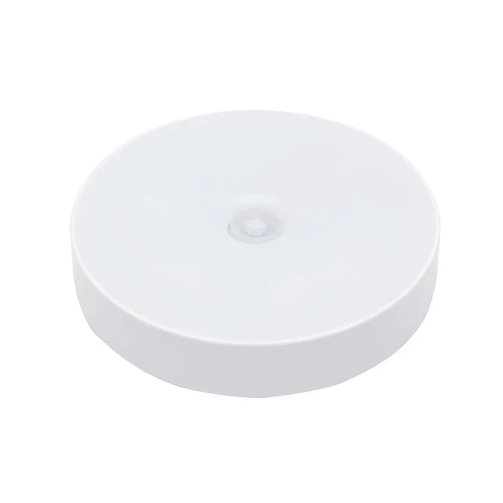 Compact round motion sensor LED night light with USB charging cable and adhesive mounting tape
