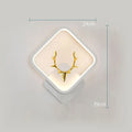Deer antler shaped wall lamp with remote control on a white wall, showing Nordic design.