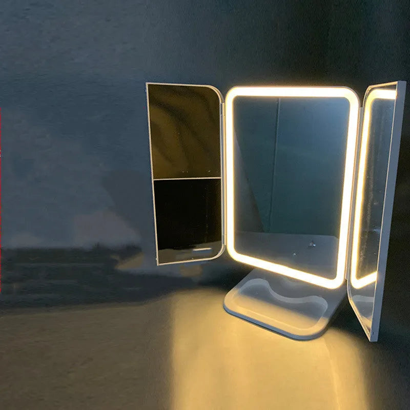 Trifold LED makeup mirror with 68 lights, 10X magnifying mirror, and USB rechargeable battery on table