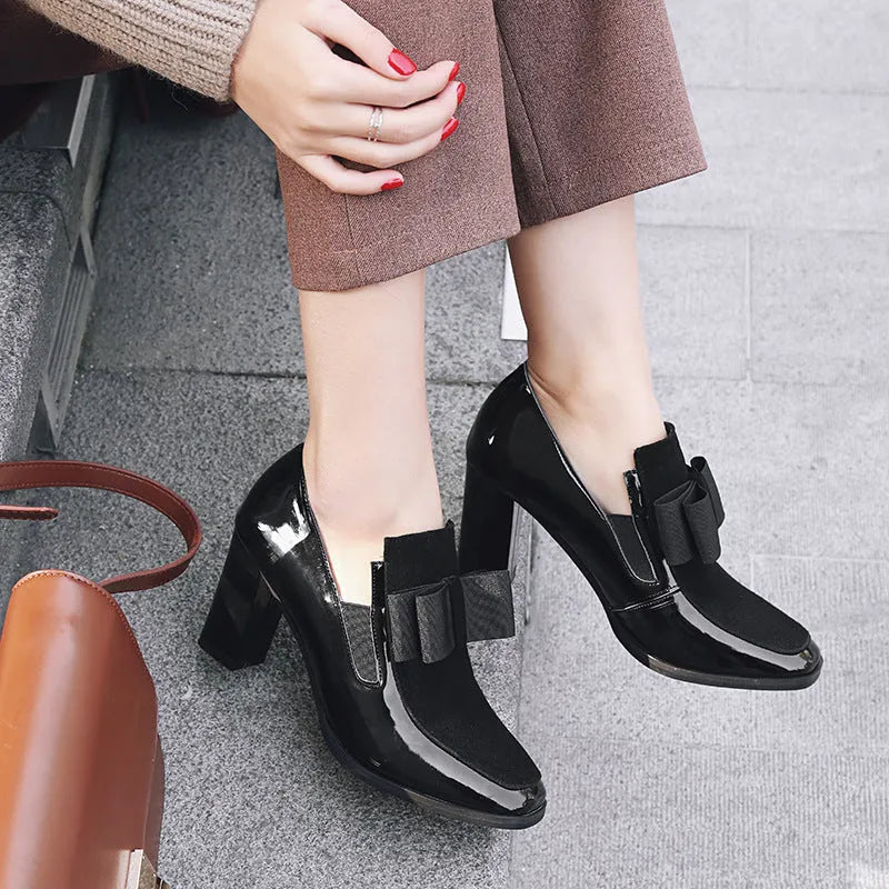 Black patent leather women's high heels with a thick square heel and rubber sole.
