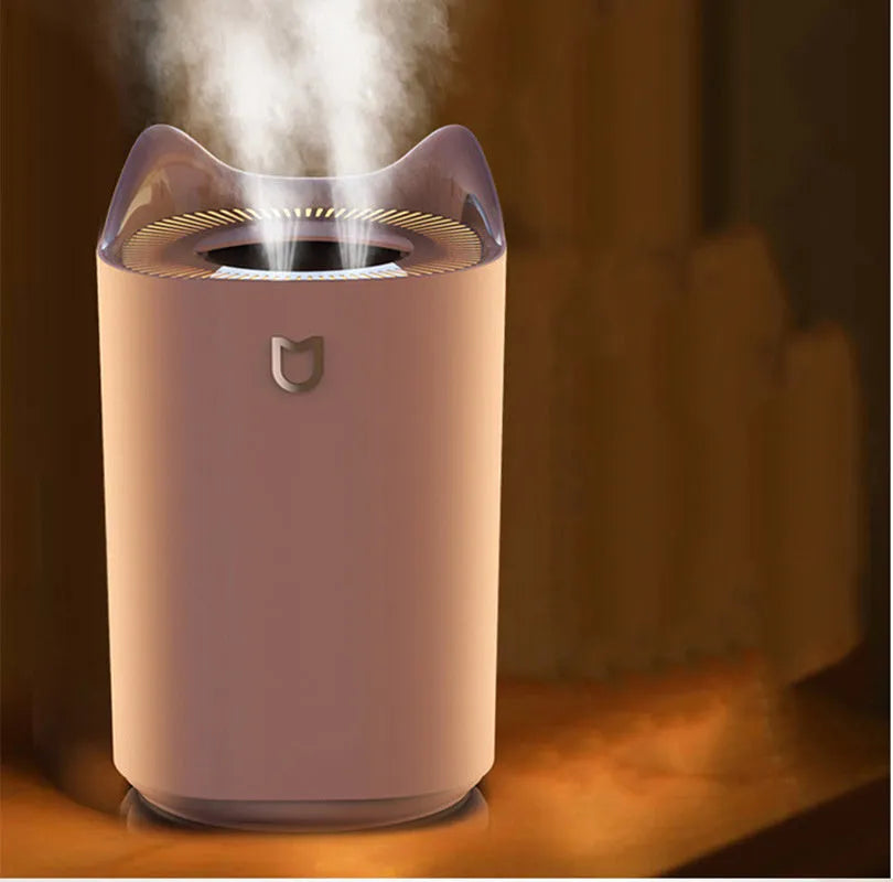 White double spray humidifier with USB cable and three mist outlets on a wooden table.