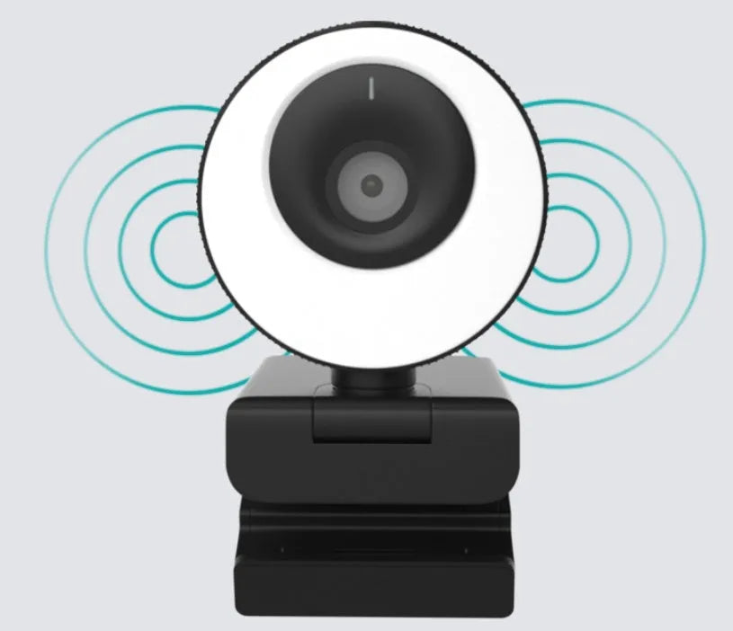 Black USB webcam with a magnetic privacy cover on a desk next to a laptop.