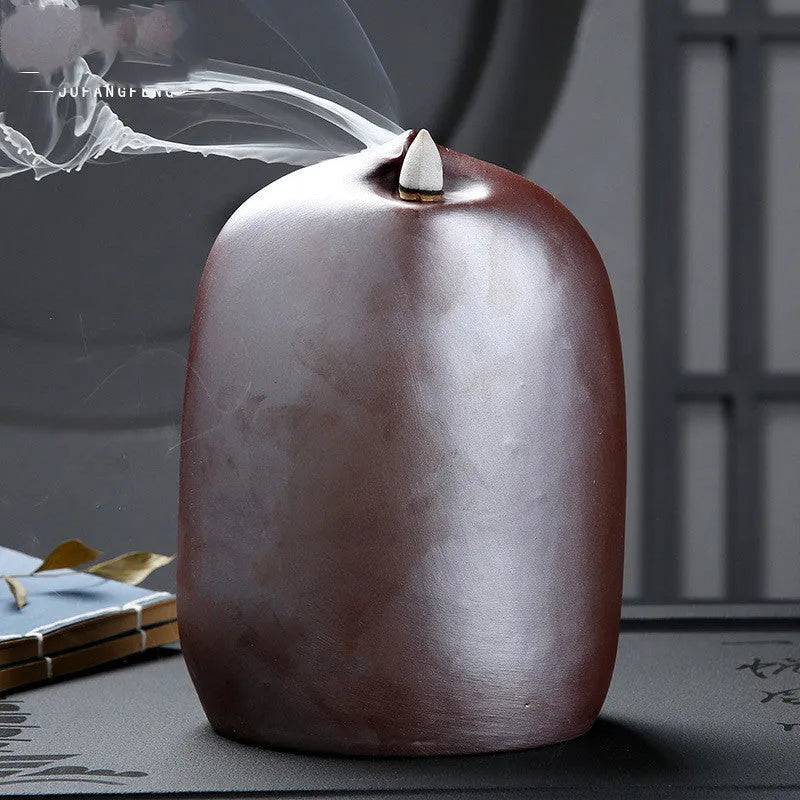 Ceramic Guanyin sitting lotus back flow incense burner with smoke cascading downward on home altar