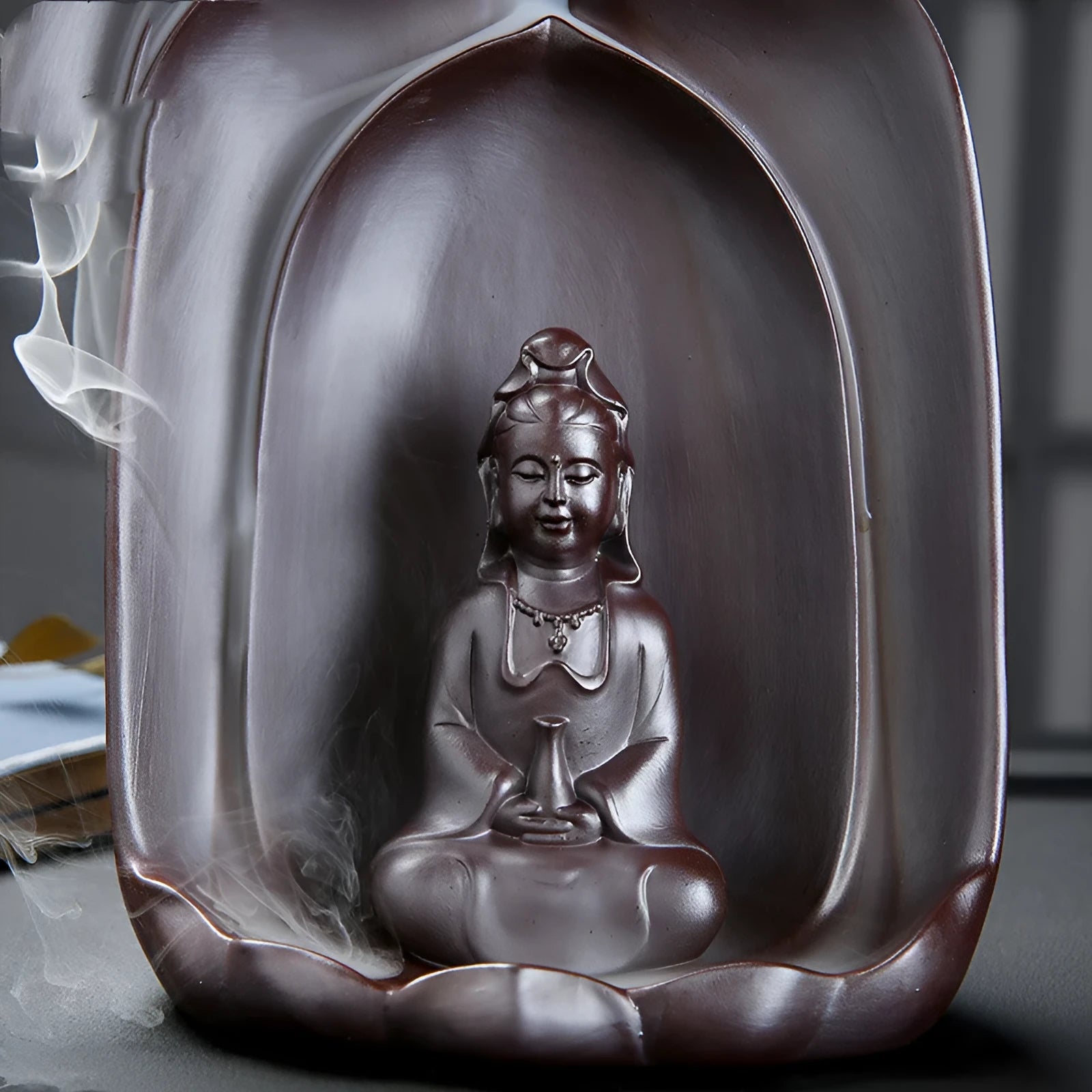 Ceramic Guanyin sitting lotus back flow incense burner with smoke cascading downward on home altar
