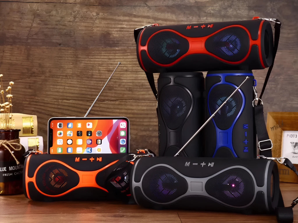 Portable black Bluetooth speaker with integrated lantern light and a fabric carrying strap attached.