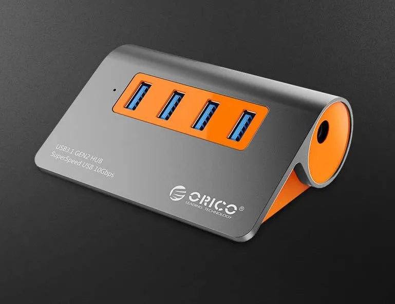 Dark grey and orange aluminium USB-C hub with four USB 3.1 ports, a DC power input, and a detachable cable.