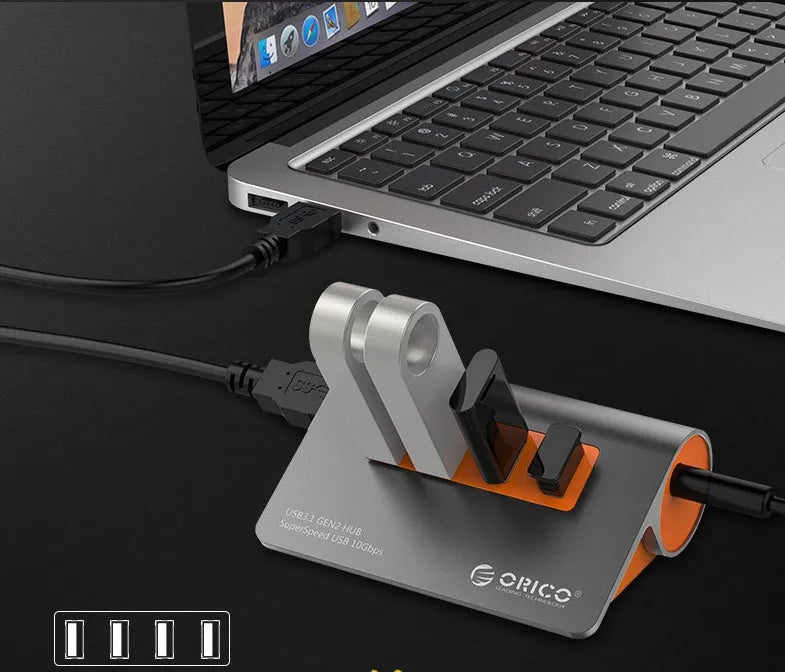 Dark grey and orange aluminium USB-C hub with four USB 3.1 ports, a DC power input, and a detachable cable.