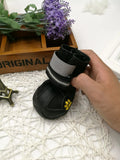 Black dog shoes with waterproof PVC sole and adjustable fuzzy belt on a dog's paw
