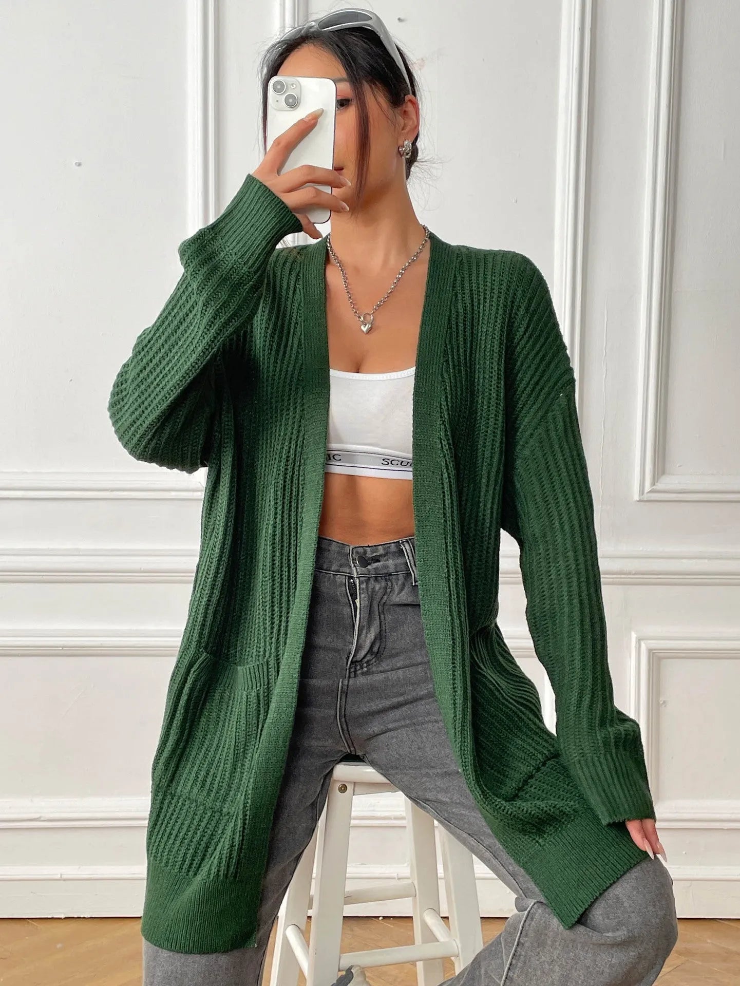Women's dark green double pocket cardigan with long sleeves and loose fit.