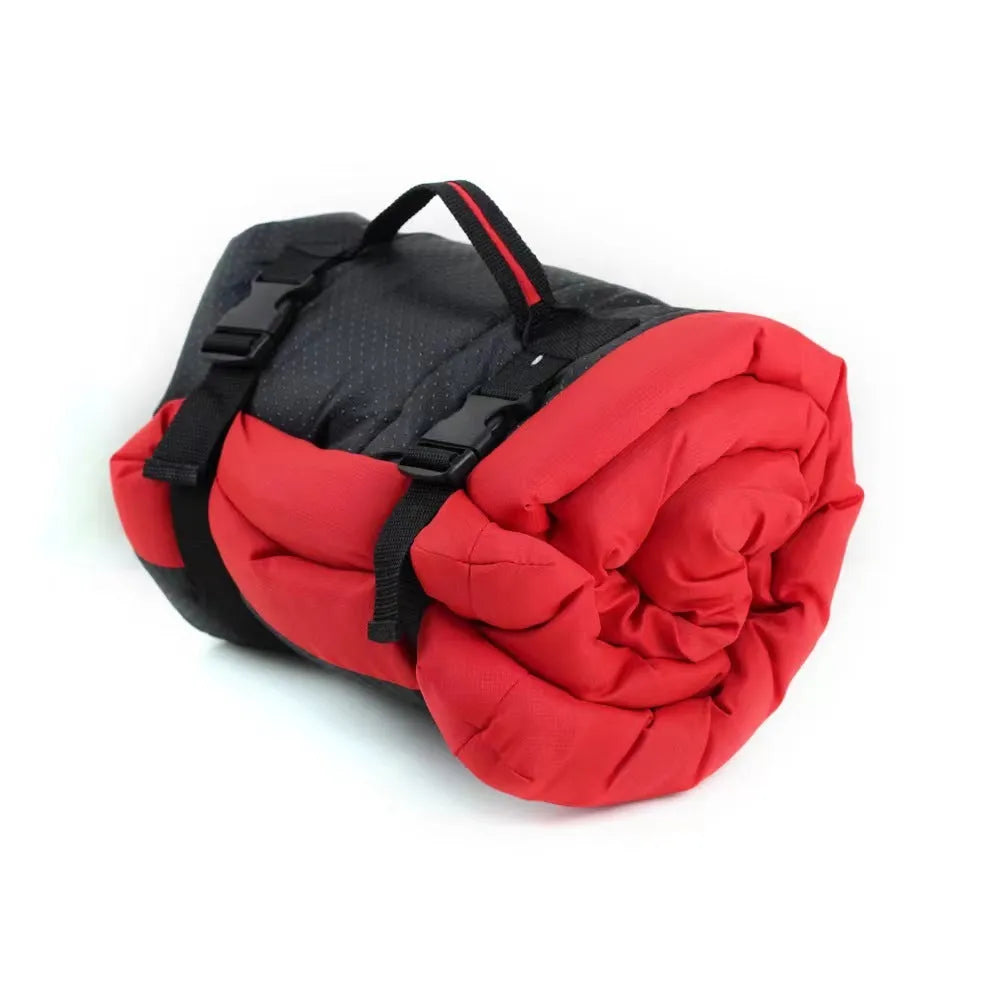 Blue folded portable dog bed with nylon buckles next to an unfolded bed on grass.
