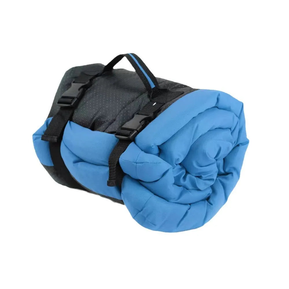 Blue folded portable dog bed with nylon buckles next to an unfolded bed on grass.